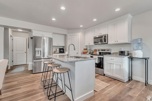 940 N Center St, Santaquin, UT 84655 - kitchen featuring appliances with stainless steel finishes, light wood finished floors, white cabinets, light stone counters, and recessed lighting