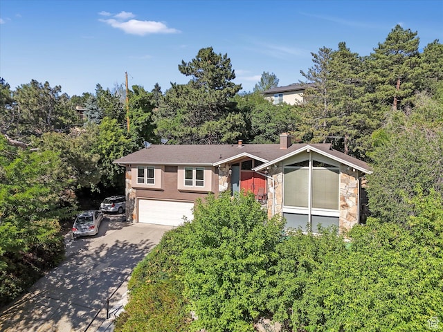 4783 S Bron Breck St, Salt Lake City, UT 84117 - view of front of property featuring stone siding, concrete driveway, an attached garage, and a chimney