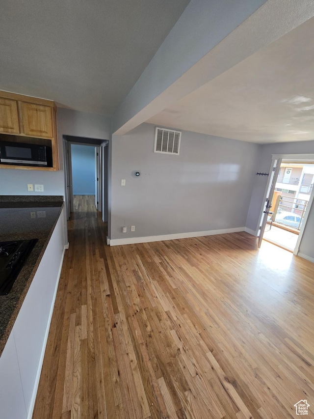 650 N 300 W Unit 206, Salt Lake City, UT 84103 - kitchen featuring stainless steel microwave, light wood-style floors, dark countertops, light brown cabinets, and black gas stovetop
