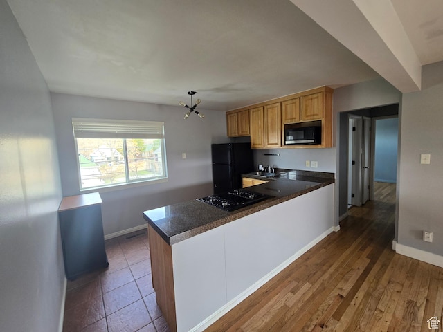 650 N 300 W Unit 206, Salt Lake City, UT 84103 - kitchen with black appliances, dark countertops, a peninsula, a chandelier, and wood finished floors