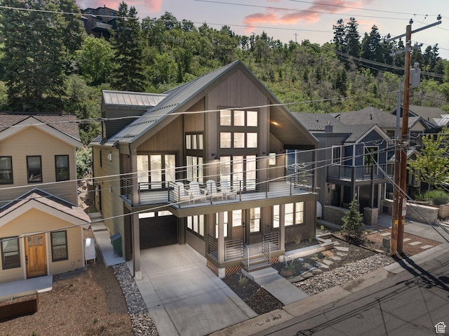 51 Daly Ave, Park City, UT 84060 - back of property at dusk with a balcony, driveway, a garage, and a metal roof