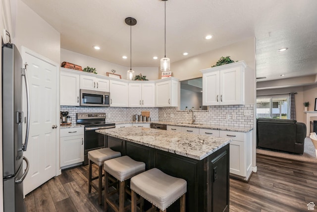 6743 W Spring Oak Dr, West Jordan, UT 84081 - kitchen featuring stainless steel appliances, white cabinetry, a kitchen island, dark wood-style flooring, and tasteful backsplash