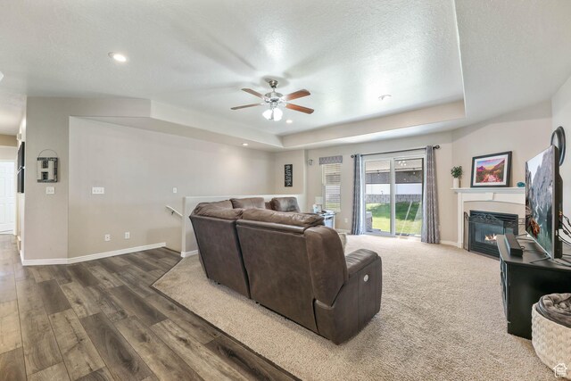6743 W Spring Oak Dr, West Jordan, UT 84081 - living room with a raised ceiling, ceiling fan, a glass covered fireplace, wood finished floors, and recessed lighting
