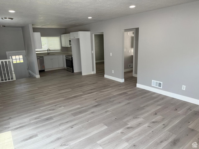 2327 S Custer E, Ogden, UT 84401 - unfurnished living room with light wood-style floors, recessed lighting, and a textured ceiling