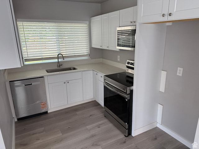 2327 S Custer E, Ogden, UT 84401 - kitchen featuring appliances with stainless steel finishes, light wood finished floors, white cabinets, and light countertops