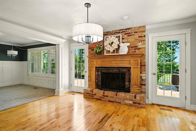 964 E Stewart Hill Dr, River Heights, UT 84321 - unfurnished living room with a chandelier, healthy amount of natural light, crown molding, light wood finished floors, and wainscoting
