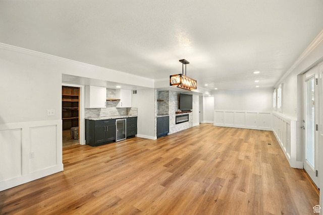 964 E Stewart Hill Dr, River Heights, UT 84321 - unfurnished living room with beverage cooler, crown molding, a decorative wall, light wood-style flooring, and wainscoting