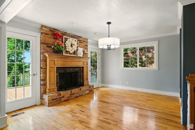 964 E Stewart Hill Dr, River Heights, UT 84321 - unfurnished living room with light wood-style floors, a textured ceiling, crown molding, a fireplace, and a chandelier