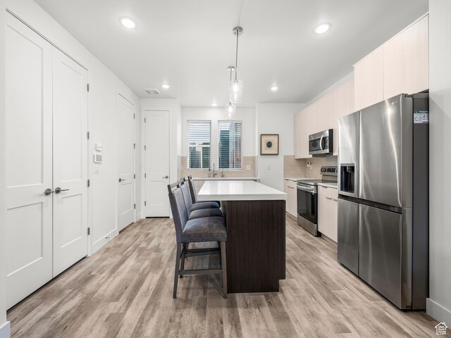 6191 W S Jordan Pkwy S Unit 286, South Jordan, UT 84009 - kitchen with stainless steel appliances, light countertops, a breakfast bar area, a kitchen island, and light wood-style flooring