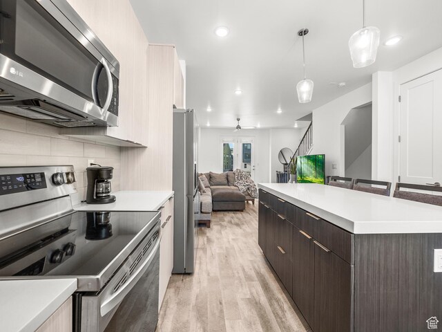 6191 W S Jordan Pkwy S Unit 286, South Jordan, UT 84009 - kitchen featuring stainless steel appliances, open floor plan, light wood-style floors, dark brown cabinets, and light countertops