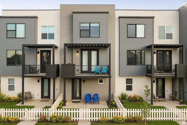 6191 W S Jordan Pkwy S Unit 286, South Jordan, UT 84009 - back of house featuring stucco siding, a balcony, a fenced front yard, and a patio area