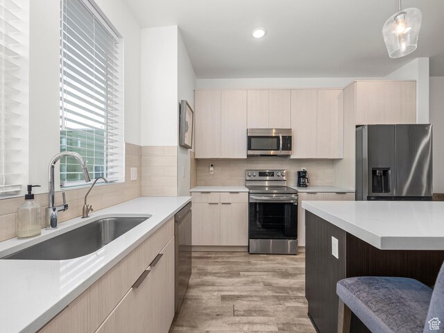 6191 W S Jordan Pkwy S Unit 286, South Jordan, UT 84009 - kitchen featuring appliances with stainless steel finishes, light brown cabinets, light countertops, light wood-type flooring, and pendant lighting