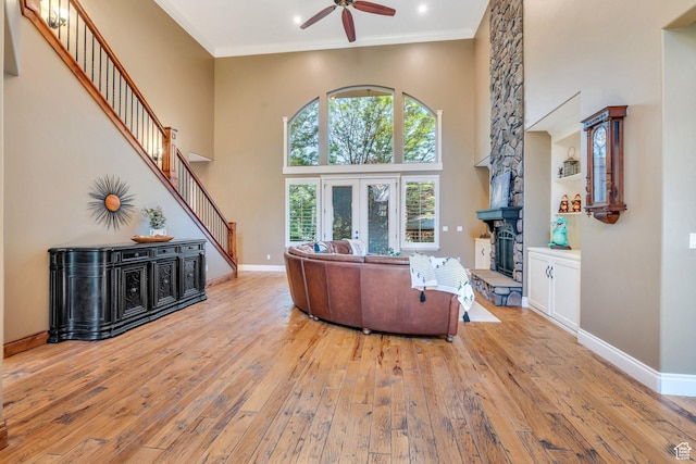 9967 N 6670 W, Highland, UT 84003 - living room featuring a ceiling fan, hardwood / wood-style floors, stairs, a stone fireplace, and a high ceiling