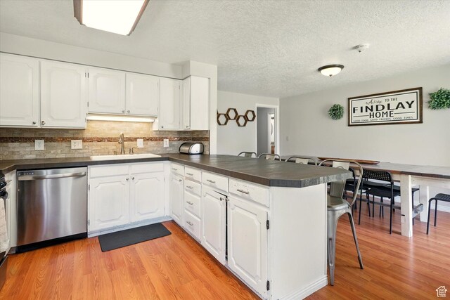 130 Summit Dr, Smithfield, UT 84335 - kitchen featuring stainless steel dishwasher, a peninsula, dark countertops, light wood finished floors, and decorative backsplash