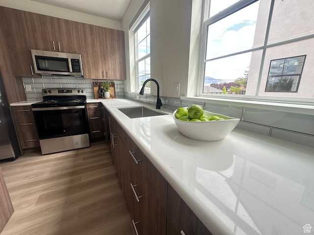 7846 S Holden St, Midvale, UT 84047 - kitchen with stainless steel appliances, light countertops, decorative backsplash, and light wood finished floors