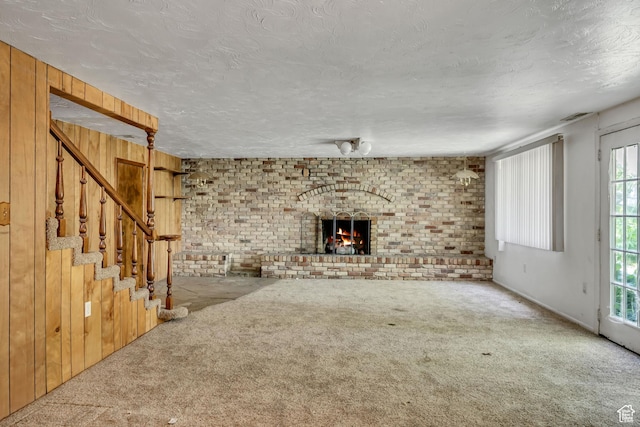 787 E 4800 S, Murray, UT 84107 - unfurnished living room featuring carpet flooring, a brick fireplace, brick wall, stairs, and wooden walls