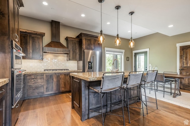 1773 E Longview Dr, Hideout, UT 84036 - kitchen featuring appliances with stainless steel finishes, wall chimney range hood, wood finished floors, dark brown cabinetry, and recessed lighting