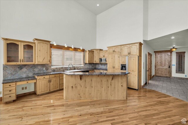 393 N Crestline Cir, St George, UT 84790 - kitchen with high vaulted ceiling, stainless steel microwave, light wood-type flooring, and light brown cabinetry
