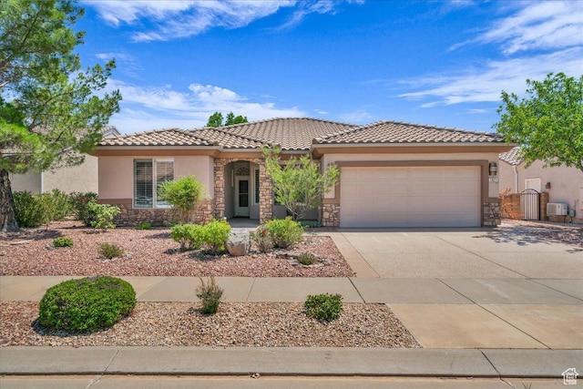 1621 W Wonderstone Dr, St George, UT 84790 - mediterranean / spanish-style home featuring stone siding, an attached garage, stucco siding, concrete driveway, and a tiled roof