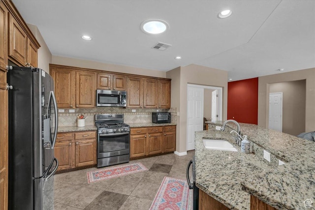 1621 W Wonderstone Dr, St George, UT 84790 - kitchen featuring stainless steel appliances, brown cabinets, backsplash, light stone counters, and recessed lighting
