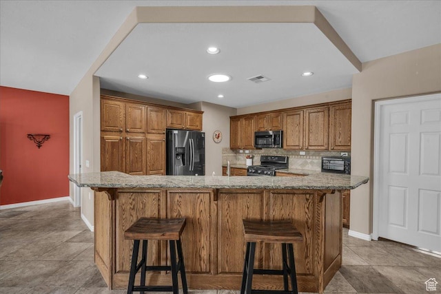 1621 W Wonderstone Dr, St George, UT 84790 - kitchen with stainless steel appliances, brown cabinets, a kitchen bar, backsplash, and recessed lighting