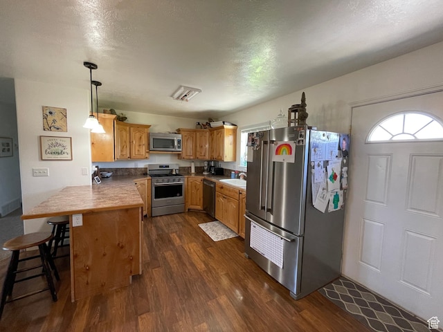 2156 W 4750 N, Roosevelt, UT 84066 - kitchen with stainless steel appliances, a peninsula, dark wood-type flooring, a kitchen breakfast bar, and pendant lighting