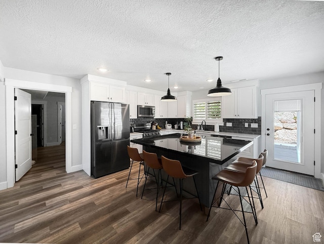 3052 N Mountain Rd, North Ogden, UT 84414 - kitchen featuring stainless steel appliances, dark wood finished floors, a textured ceiling, decorative backsplash, and a kitchen bar