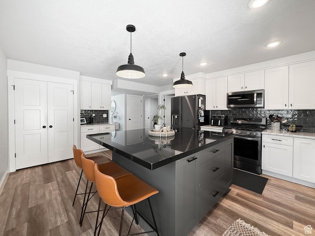 3052 N Mountain Rd, North Ogden, UT 84414 - kitchen with appliances with stainless steel finishes, decorative backsplash, wood finished floors, white cabinets, and a textured ceiling