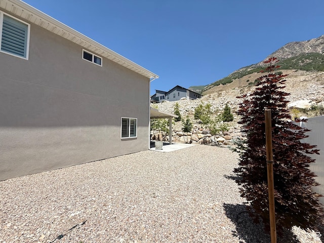 3052 N Mountain Rd, North Ogden, UT 84414 - view of side of home with a patio, a mountain view, and stucco siding