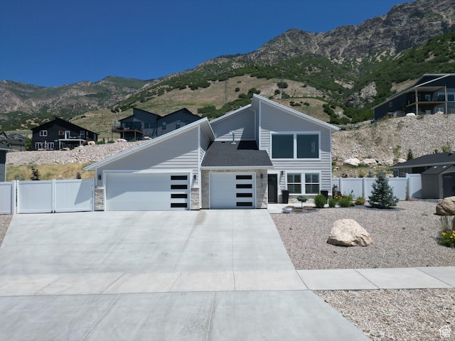3052 N Mountain Rd, North Ogden, UT 84414 - view of front facade featuring an attached garage, concrete driveway, a mountain view, a gate, and stone siding