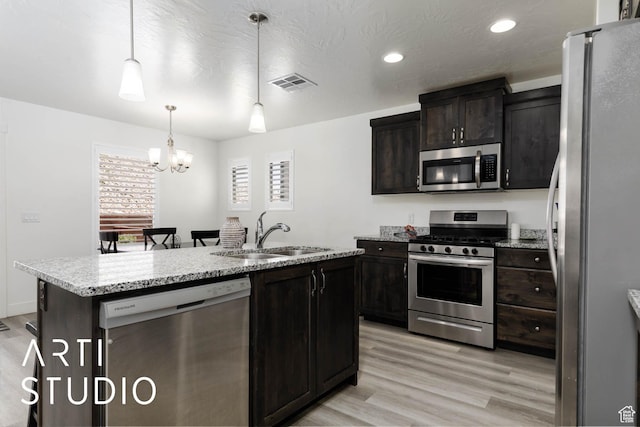 6297 S Zelda Dr, St George, UT 84790 - kitchen with appliances with stainless steel finishes, a chandelier, light wood finished floors, a center island with sink, and pendant lighting