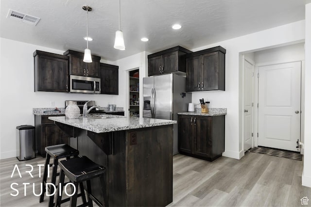 6297 S Zelda Dr, St George, UT 84790 - kitchen featuring appliances with stainless steel finishes, light wood-type flooring, light stone countertops, a breakfast bar area, and recessed lighting