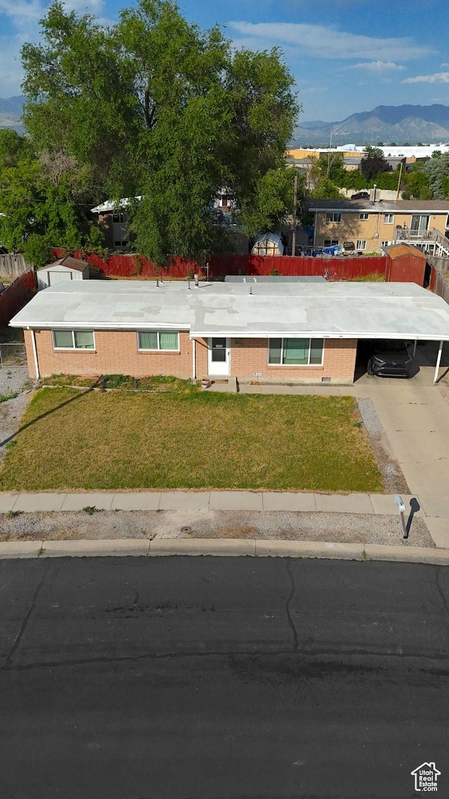 2617 S Ridgeland W, West Valley City, UT 84119 - view of front of home featuring a mountain view, a front lawn, brick siding, and an attached carport
