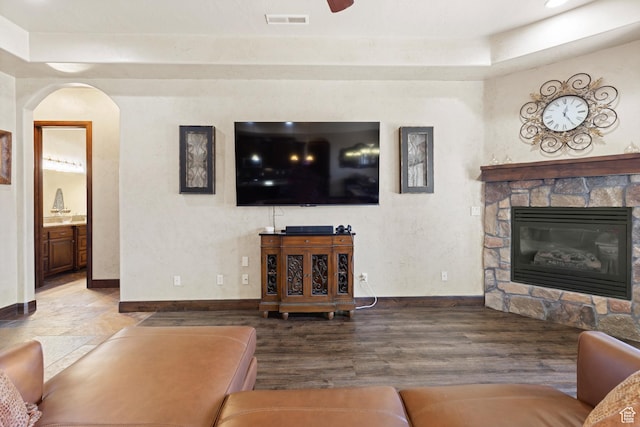 1883 S Purple Sage Dr, Washington, UT 84780 - living area featuring a stone fireplace, arched walkways, wood finished floors, and a raised ceiling