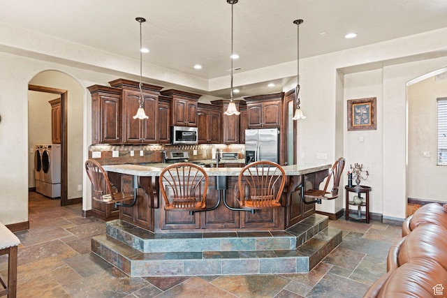 1883 S Purple Sage Dr, Washington, UT 84780 - kitchen with appliances with stainless steel finishes, arched walkways, stone tile flooring, and separate washer and dryer