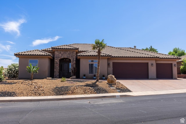 1883 S Purple Sage Dr, Washington, UT 84780 - mediterranean / spanish-style home with an attached garage, stucco siding, driveway, stone siding, and a tiled roof