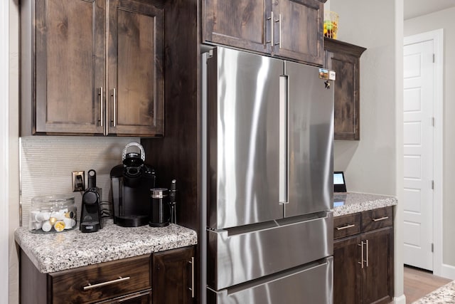 2723 S Varano Way, St George, UT 84770 - kitchen featuring freestanding refrigerator, dark brown cabinets, tasteful backsplash, light stone counters, and light wood-style flooring