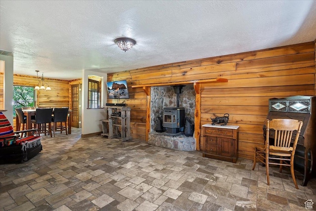 409 N 9000 E, Huntsville, UT 84317 - living room with wooden walls, a wood stove, a chandelier, a textured ceiling, and stone finish floors