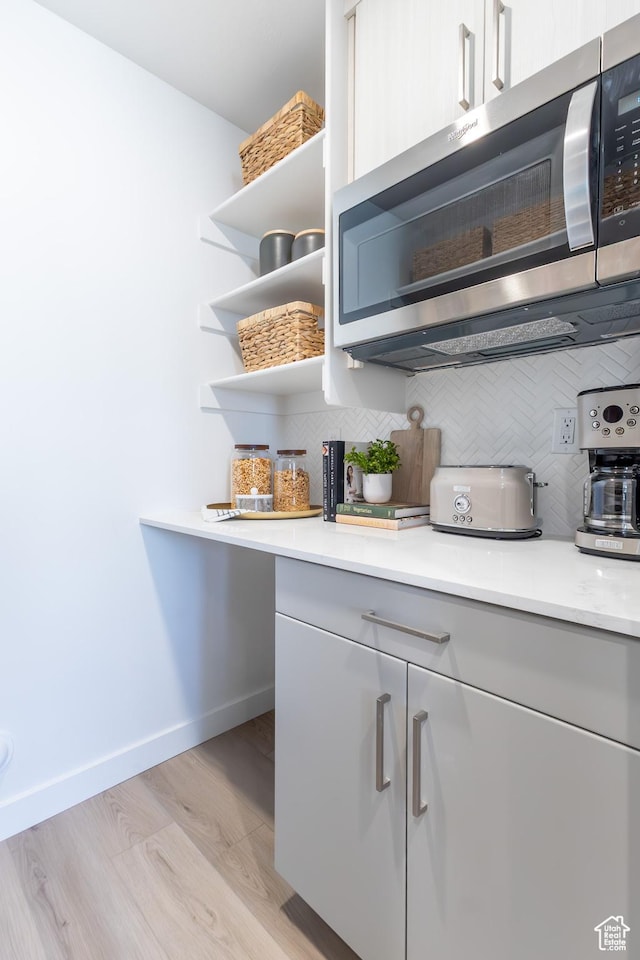 2719 N 2775 W Unit 120, Plain City, UT 84404 - kitchen with stainless steel microwave, decorative backsplash, open shelves, light countertops, and light wood-type flooring