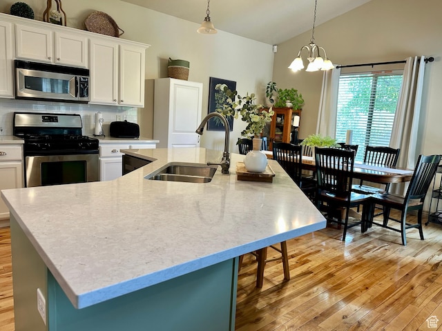 12413 S Andreas St W, Riverton, UT 84065 - kitchen featuring appliances with stainless steel finishes, a kitchen island with sink, vaulted ceiling, light wood-style floors, and white cabinetry