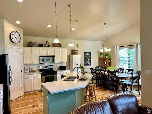 12413 S Andreas St W, Riverton, UT 84065 - kitchen featuring appliances with stainless steel finishes, light wood finished floors, a kitchen bar, lofted ceiling, and a chandelier