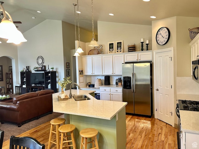 12413 S Andreas St W, Riverton, UT 84065 - kitchen featuring appliances with stainless steel finishes, arched walkways, a kitchen bar, white cabinets, and high vaulted ceiling