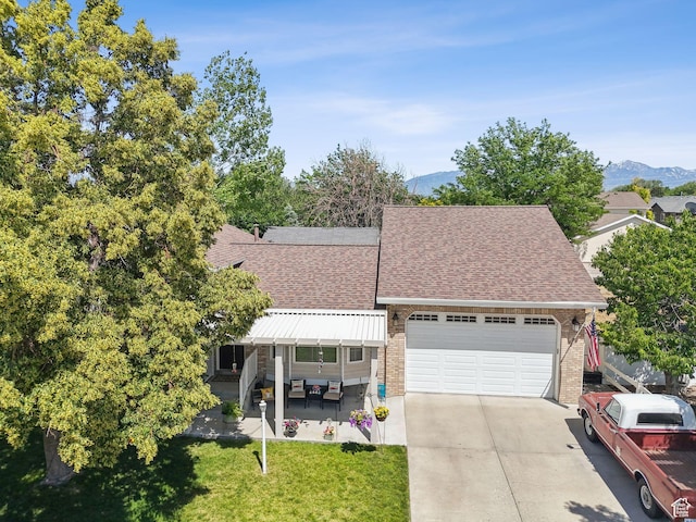 3573 S Deann Dr W, West Valley City, UT 84128 - view of front of home featuring a shingled roof, an attached garage, concrete driveway, a mountain view, and a front lawn