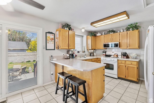 3573 S Deann Dr W, West Valley City, UT 84128 - kitchen featuring white appliances, light tile patterned flooring, a kitchen breakfast bar, and light countertops
