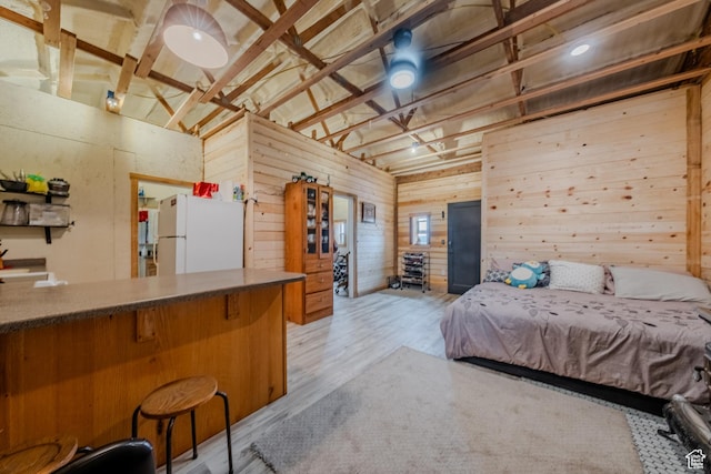 7395 N Johnson Canyon Rd, Kanab, UT 84741 - bedroom featuring freestanding refrigerator, wooden walls, vaulted ceiling, and light wood-style flooring