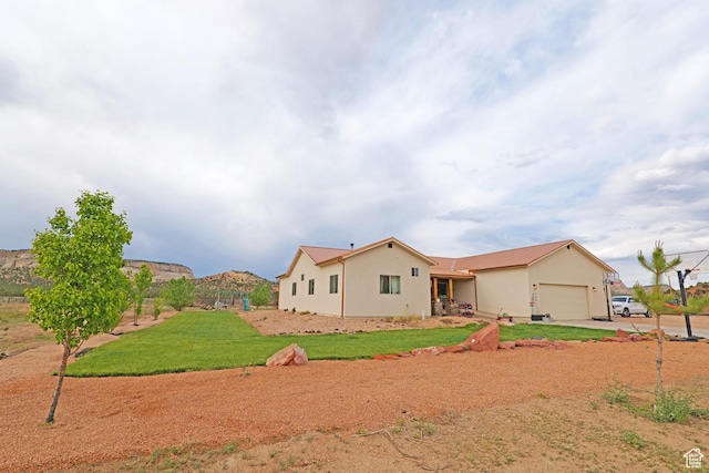 7395 N Johnson Canyon Rd, Kanab, UT 84741 - back of house with a garage, a yard, driveway, and stucco siding