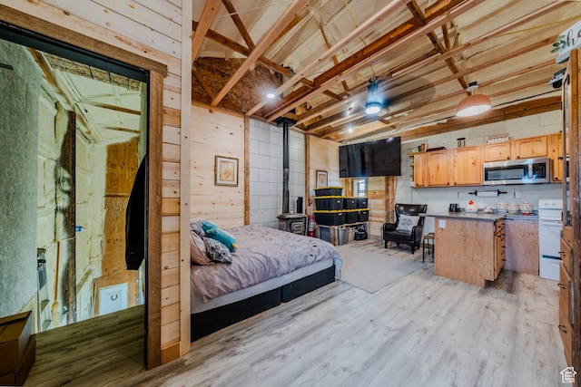 7395 N Johnson Canyon Rd, Kanab, UT 84741 - bedroom with a wood stove, wood walls, and light wood-style floors