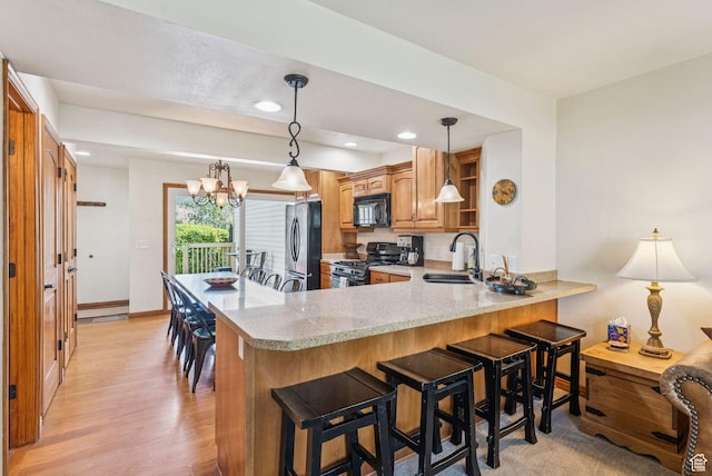 171 Dunlop Ct, Park City, UT 84060 - kitchen featuring black microwave, gas range, freestanding refrigerator, a peninsula, and light stone countertops