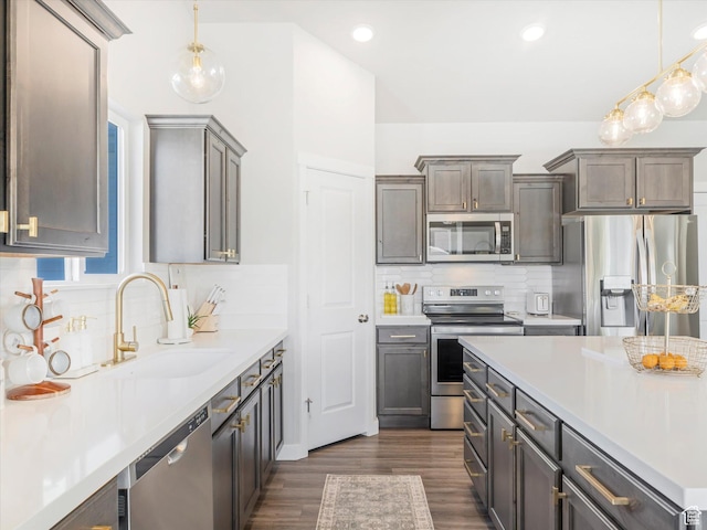 2297 N 250 W, Tooele, UT 84074 - kitchen with appliances with stainless steel finishes, light countertops, backsplash, decorative light fixtures, and dark wood-type flooring