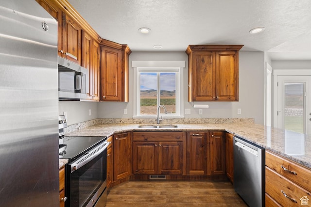 18605 N 6000 W, Riverside, UT 84334 - kitchen featuring appliances with stainless steel finishes, dark wood finished floors, brown cabinets, light stone countertops, and recessed lighting